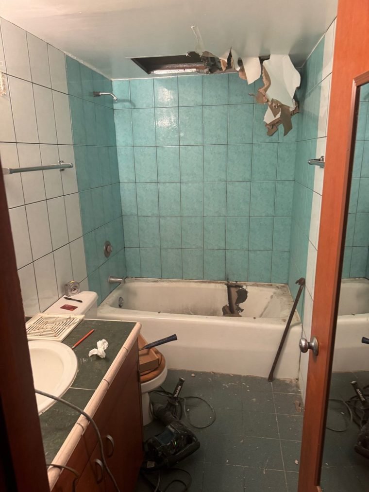 The bathroom stripped out: turquoise tile, the ceiling opened up and the tub being removed