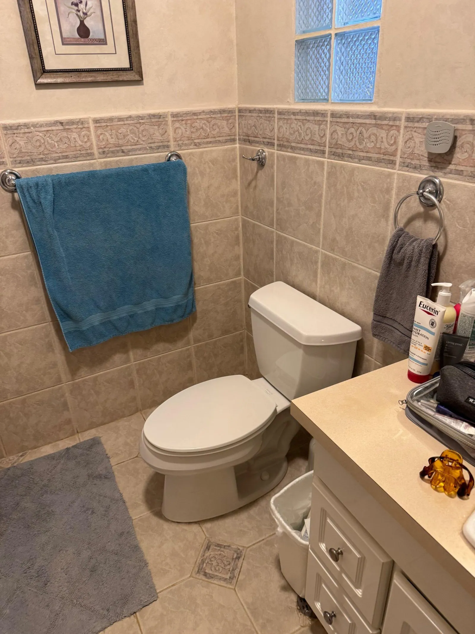 Beige tiled bathroom with a decorative border course, a glass block window and a cream laminate vanity
