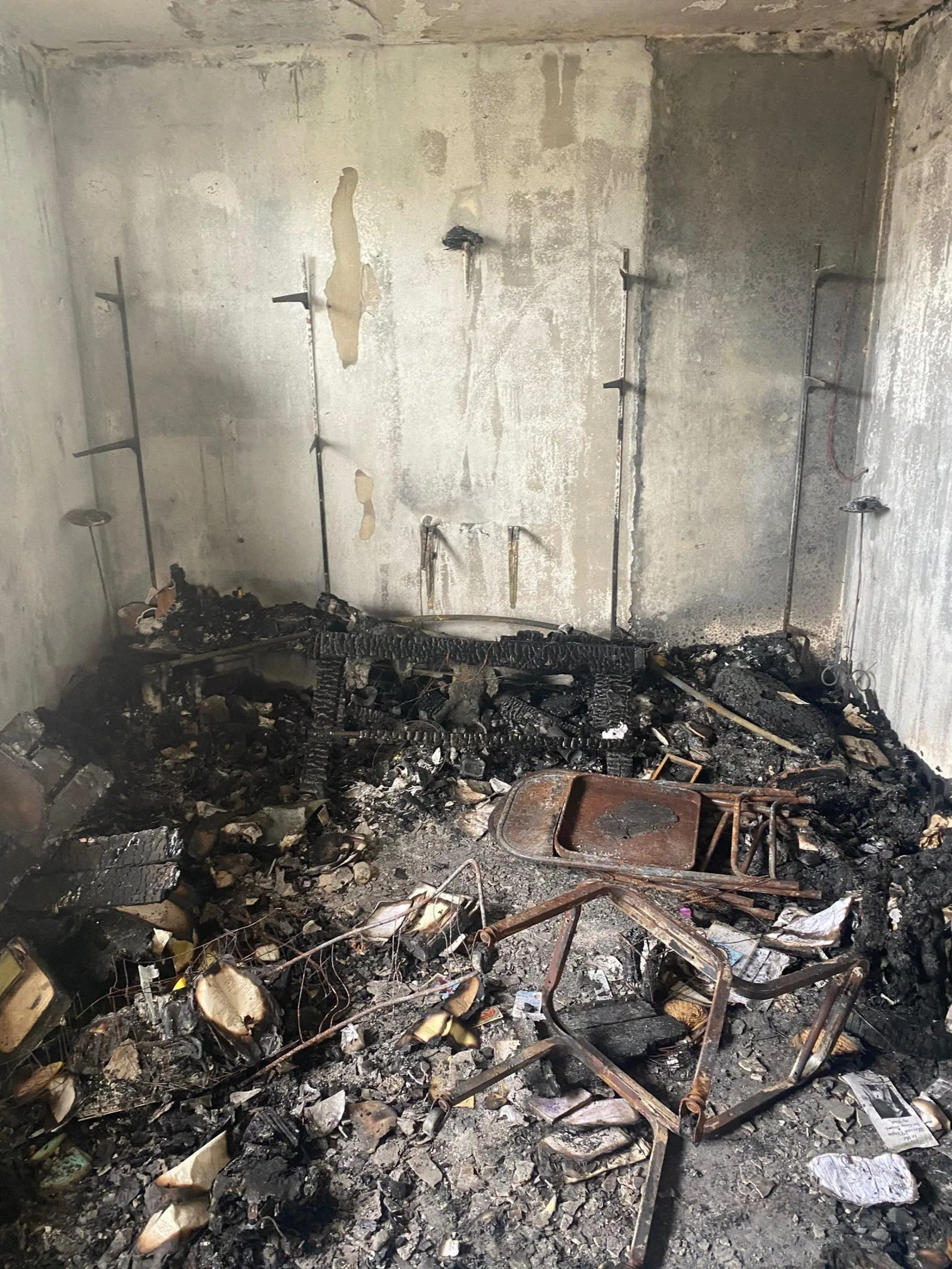 Fire-gutted concrete room, soot-blackened walls, the floor buried in charred debris