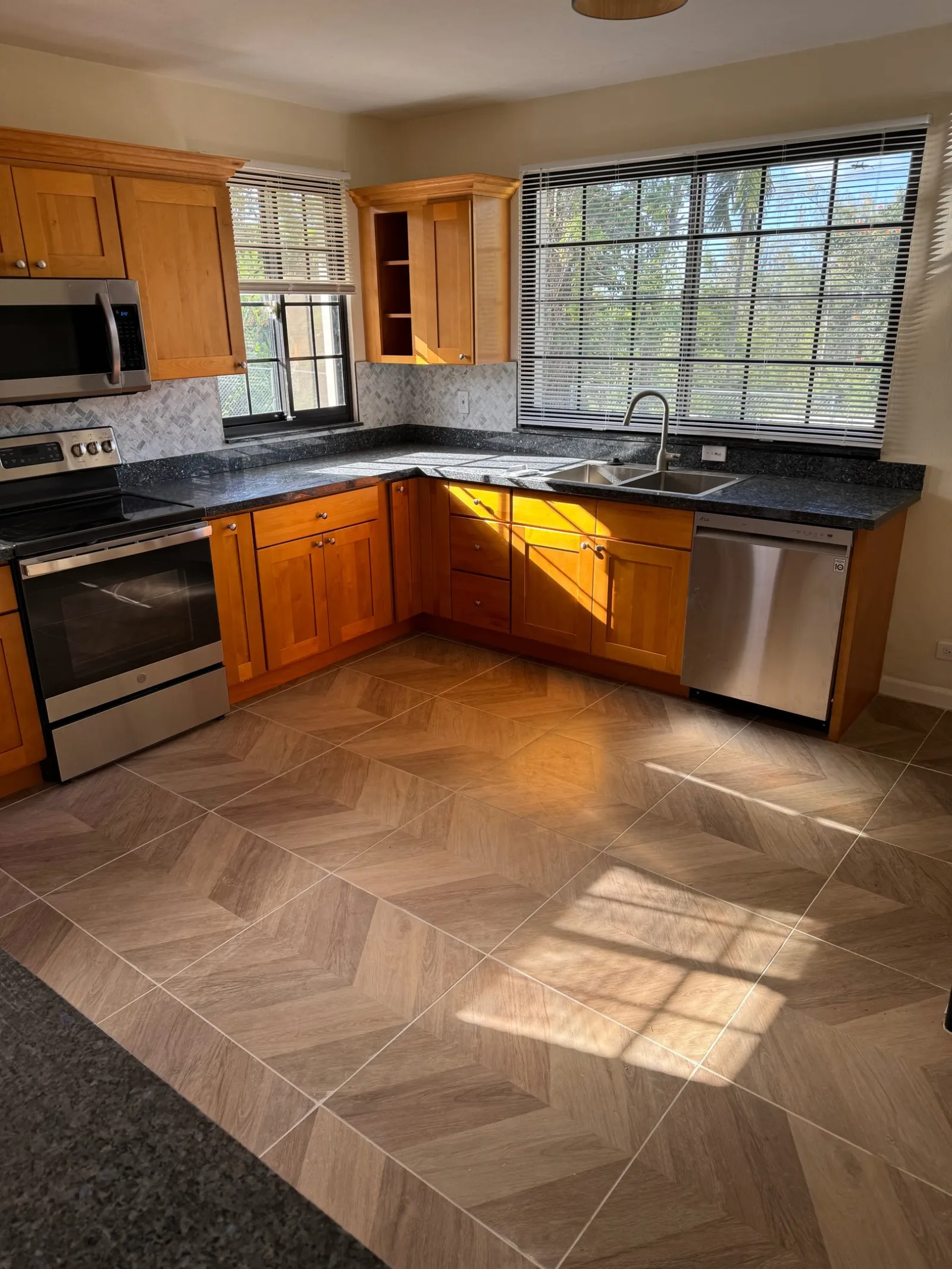 Honey shaker cabinets with a herringbone backsplash and chevron floor tile.