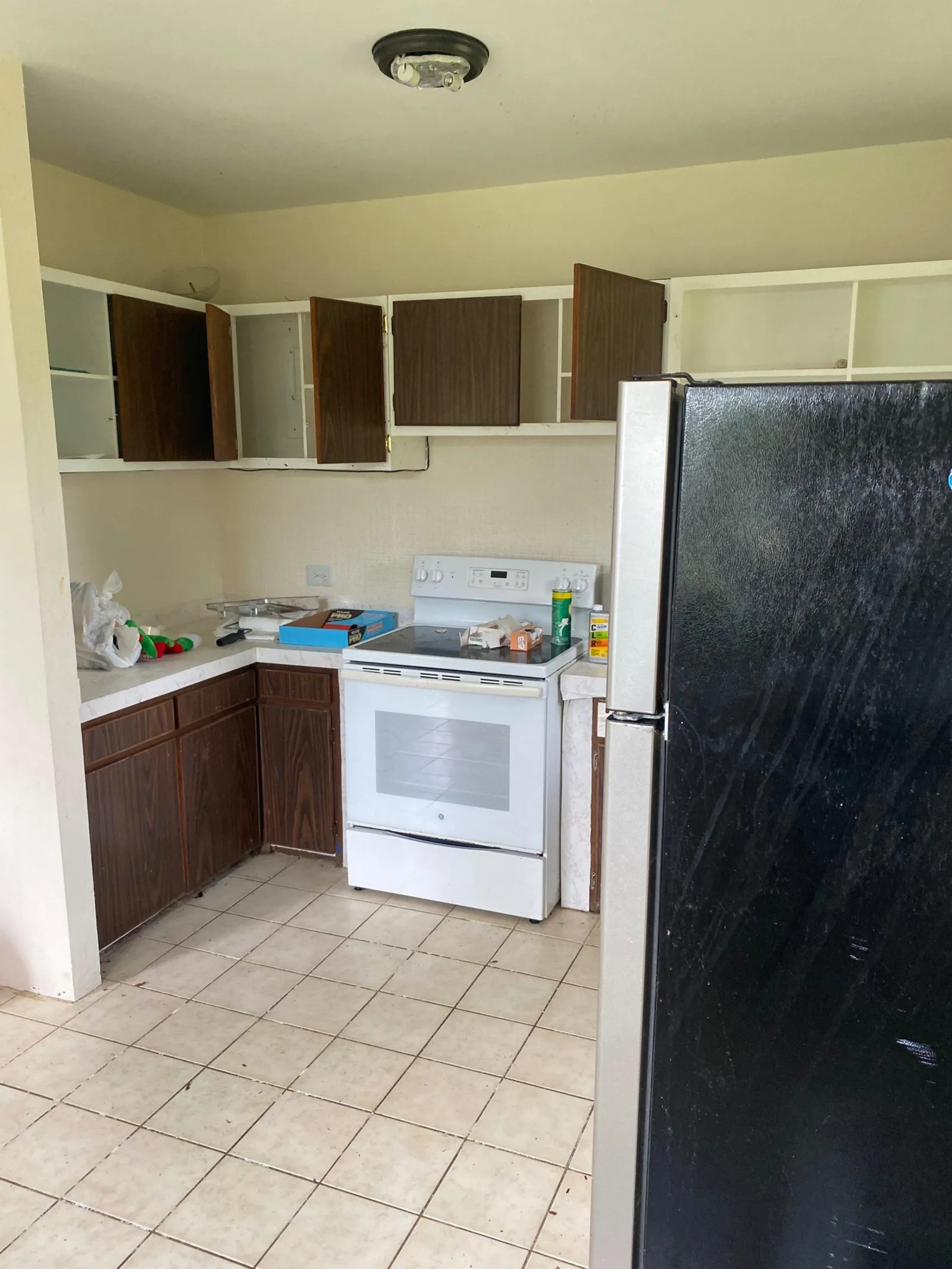 Dated kitchen with dark woodgrain cabinets, a white electric range and stained square floor tile